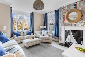 A living room with a fireplace, a sofa set, a coffee table, and a patterned wall.