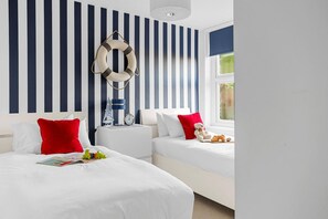 A hotel room with two beds, striped wallpaper, a life preserver decoration, a clock, and a window with a view.