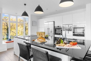A modern kitchen with a central island, stainless steel appliances, and pendant lighting.