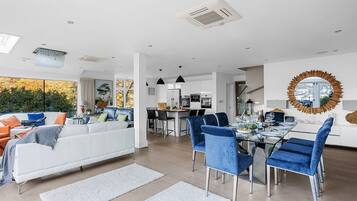 A modern living space with a dining area, kitchen, and a large window overlooking greenery.