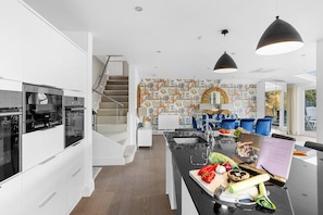 A modern kitchen with a central island, stainless steel appliances, and a dining area with blue chairs.