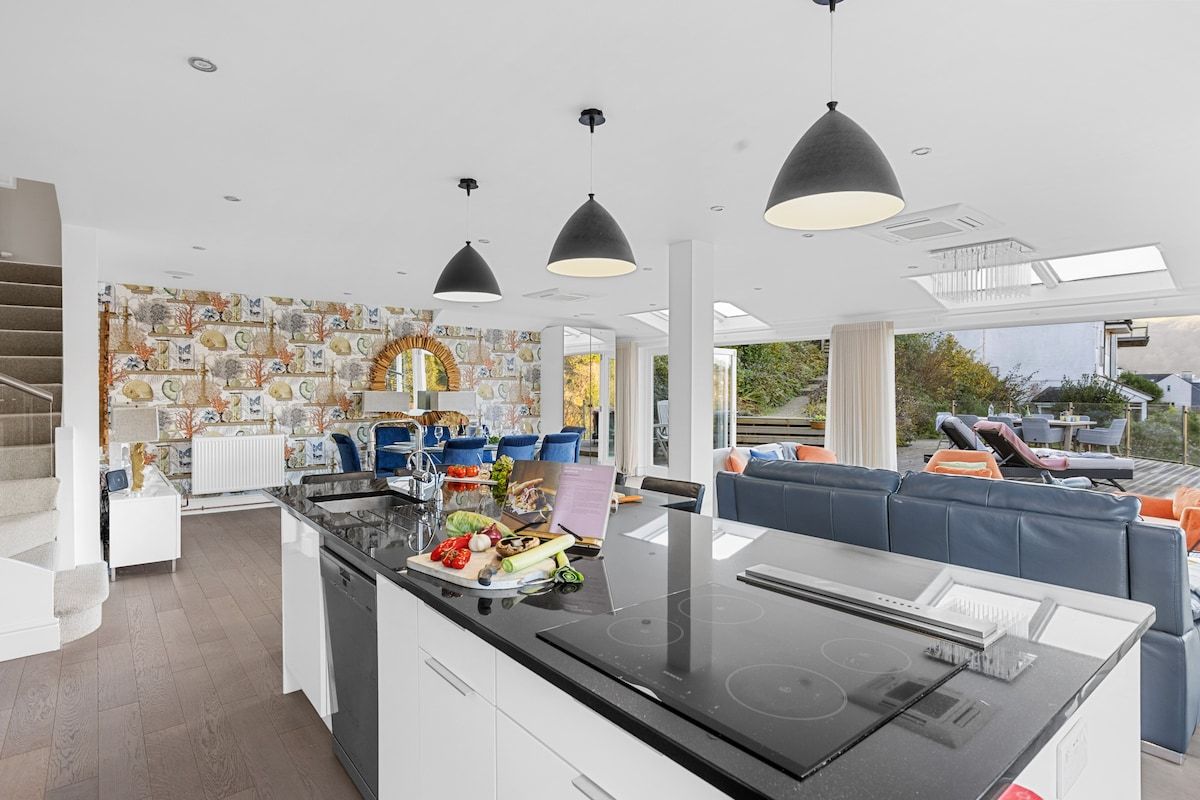 A modern kitchen with a central island, pendant lighting, and a view of the outdoors.