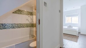 Ein modernes Badezimmer mit Duschkabine aus Glas, einer weißen Toilette und einer Badewanne.