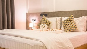 A bedroom with a wooden bed, a nightstand, a lamp, and patterned pillows. - Holiday Crib (Dhiffushi)