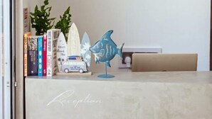 A reception desk with a 'Reception' sign, a blue fish decoration, a surfboard, and a small car model. - Holiday Crib (Dhiffushi)