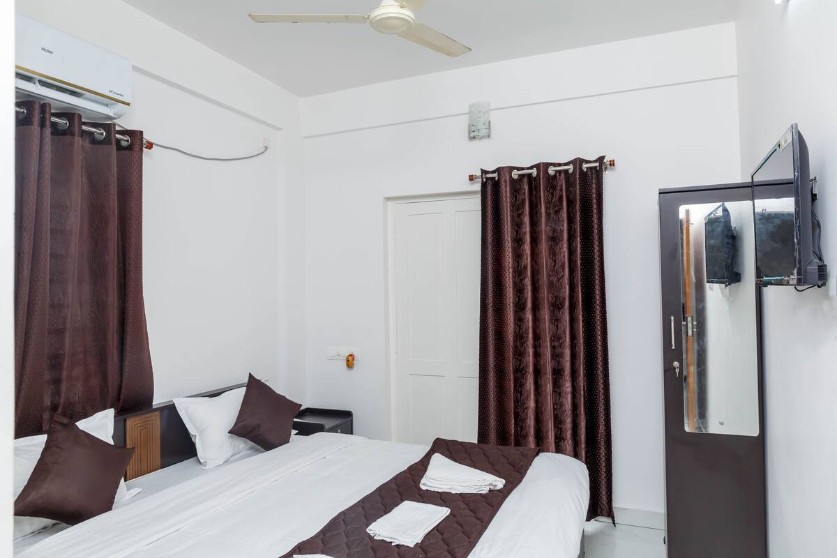 A hotel room with a bed, a wardrobe, a mirror, and a ceiling fan.