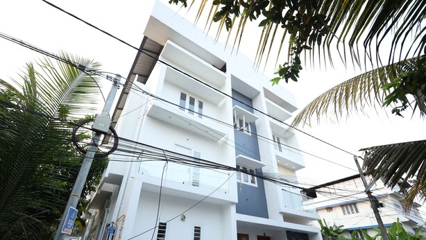 A multi-story residential building with balconies, surrounded by greenery. - Guest West Inn (Kanayannur)