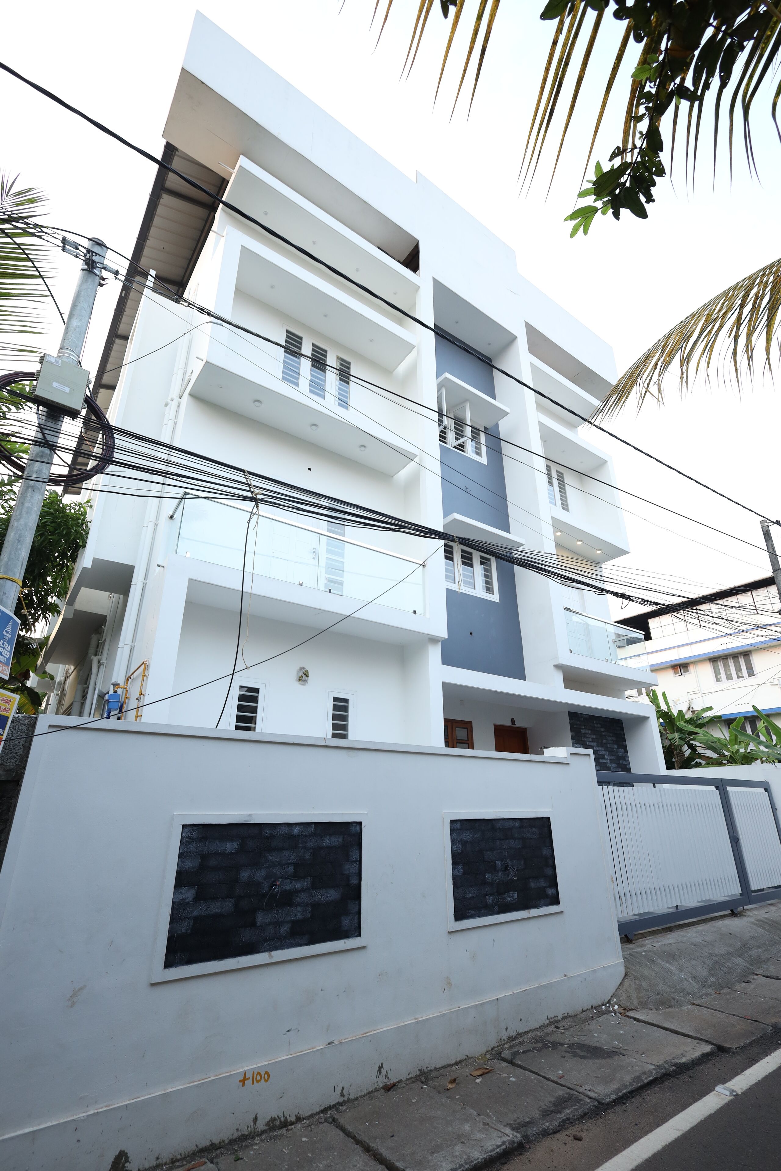 A multi-story residential building with balconies, a gated entrance, and a white exterior.