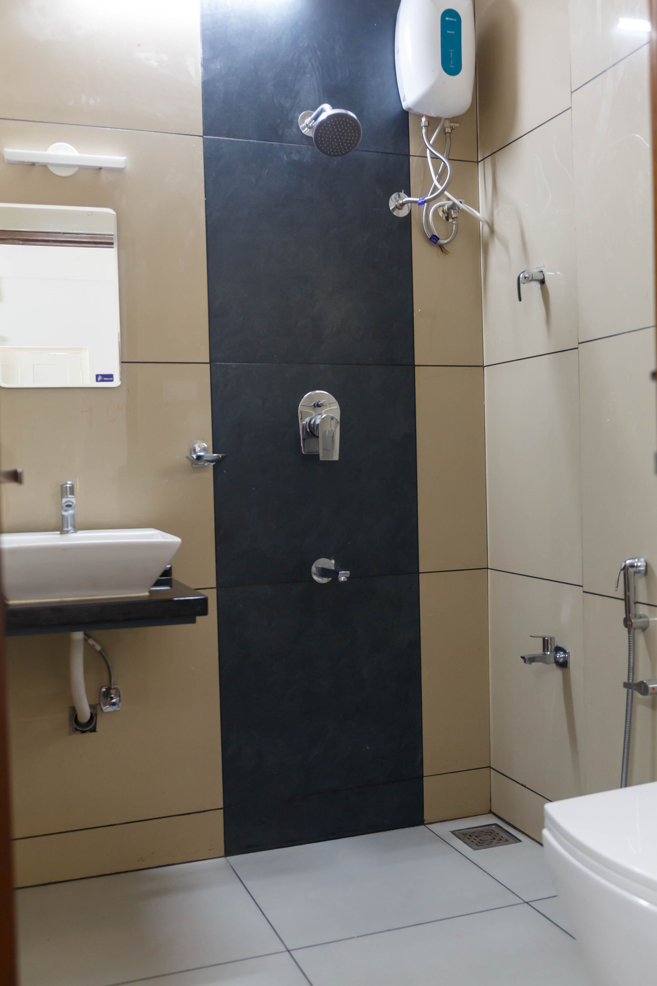 Un baño con lavabo, espejo, dispensador de toallas, ducha e inodoro.