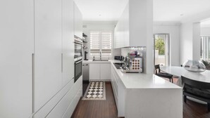 Una cocina moderna con armarios blancos, una isla central y una zona de comedor con mesa y sillas.