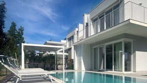 Une maison moderne dotée d’une piscine, d’un espace salon extérieur et d’un patio couvert.