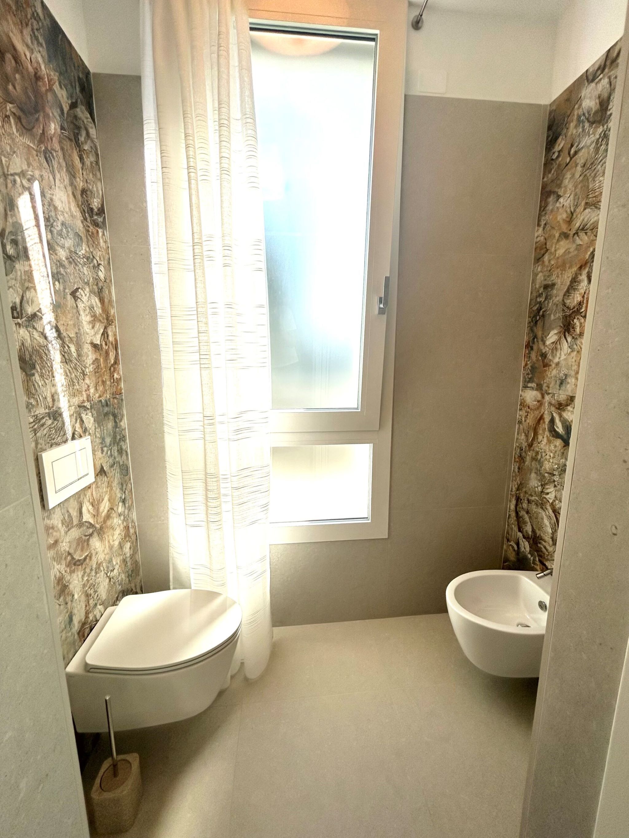 Een badkamer met twee wastafels, een raam met geëtste glas en een douchehoek.
