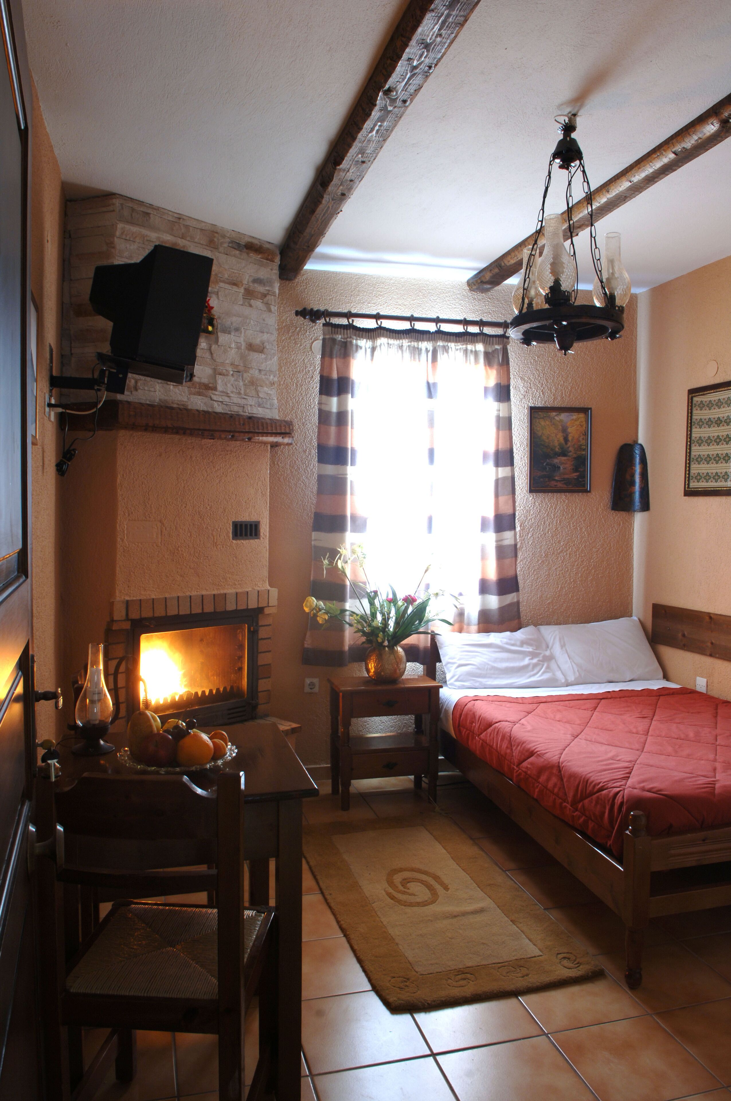 Ein gemütliches Zimmer mit Kamin, einem Bett, einem Esstisch mit Stühlen und einer Pendelleuchte.