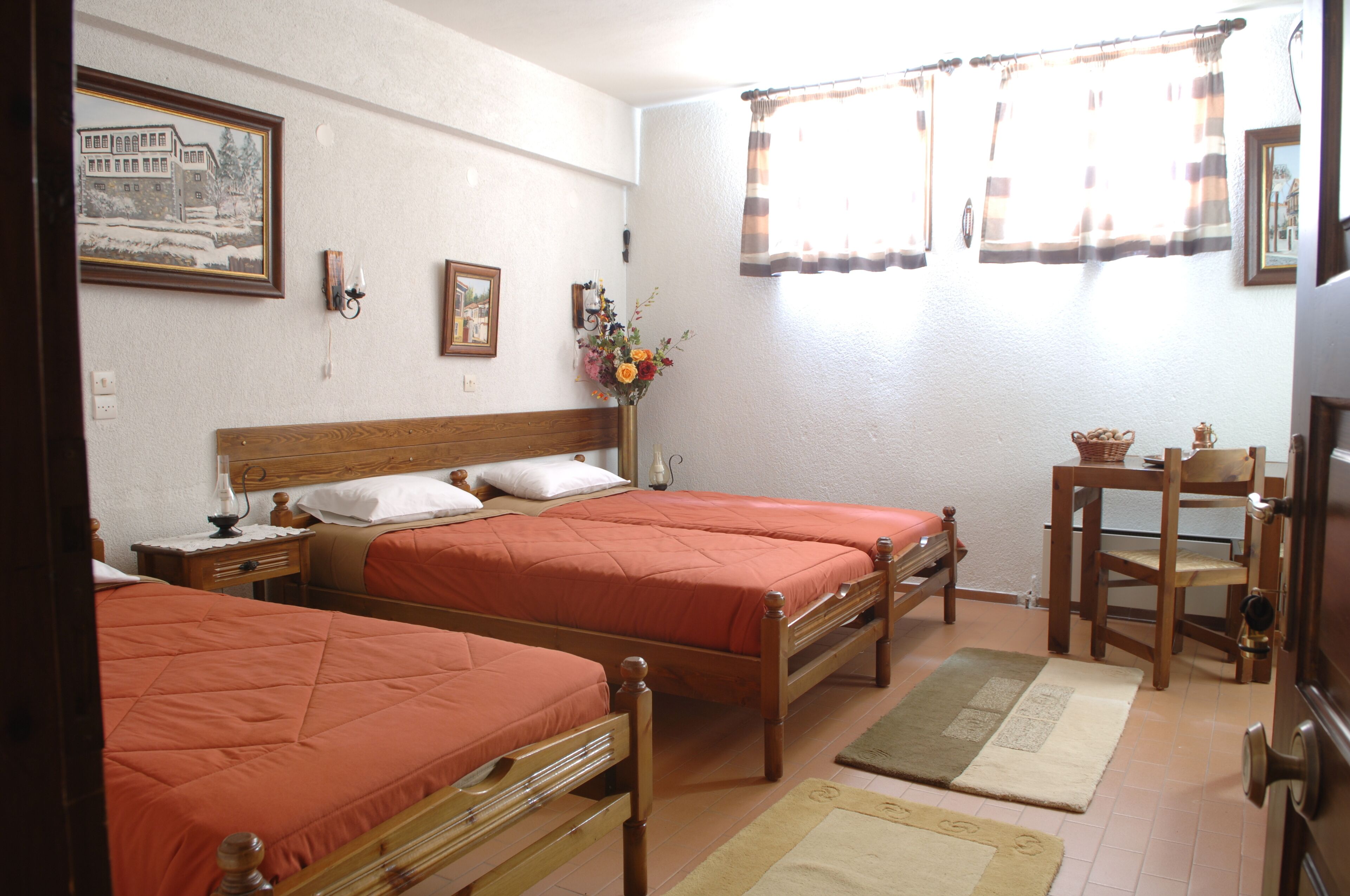 A room with two wooden beds, a wooden nightstand, a small table with a basket, and a chair.