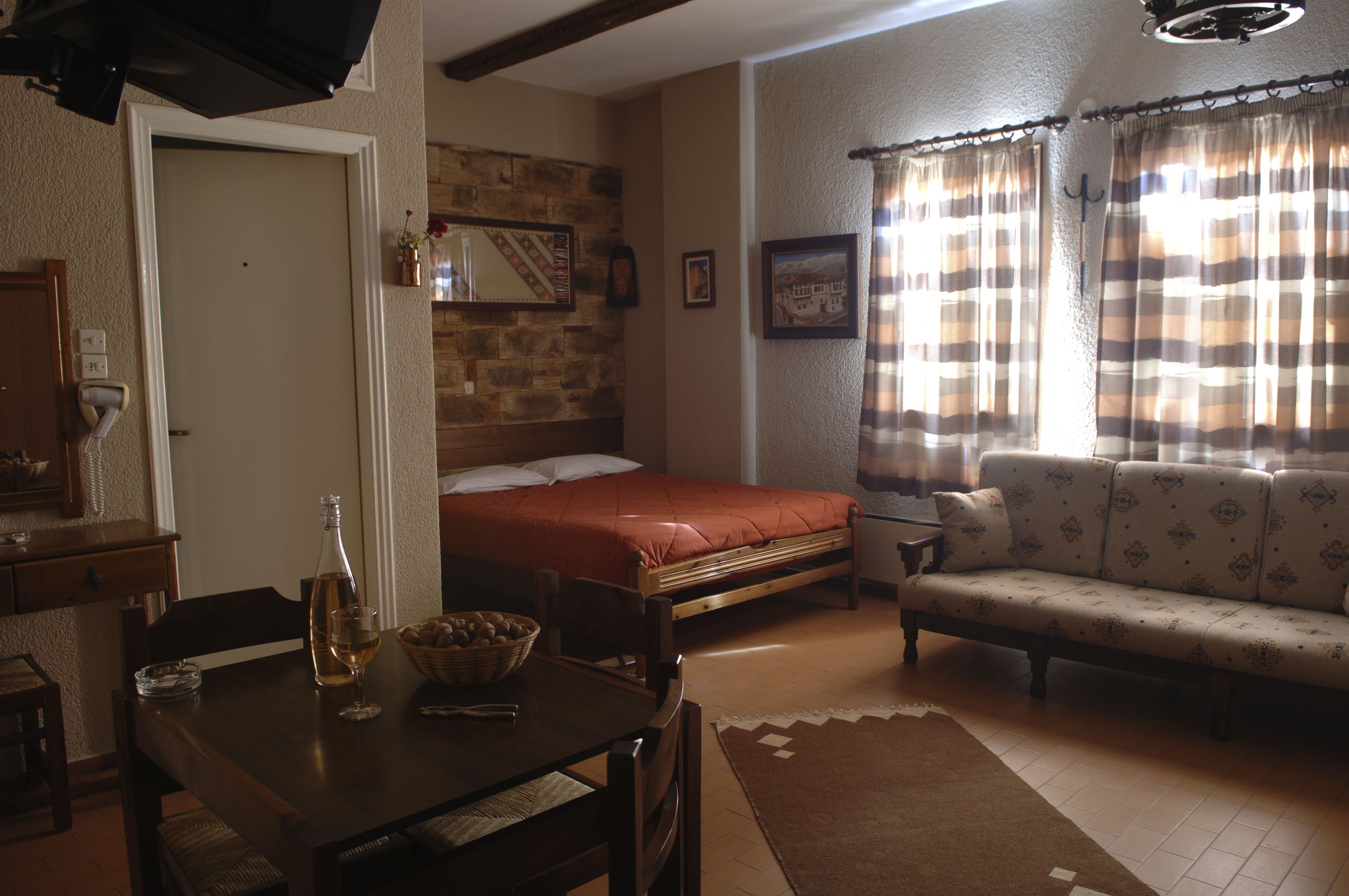 A cozy living room with a sofa, a dining table with a bottle and glasses, a bed, and a fireplace.