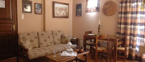 Una sala acogedora con sofá, mesa de centro de madera y comedor.