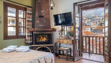Una habitación con chimenea, cama, televisor y balcón con vistas a la ciudad.