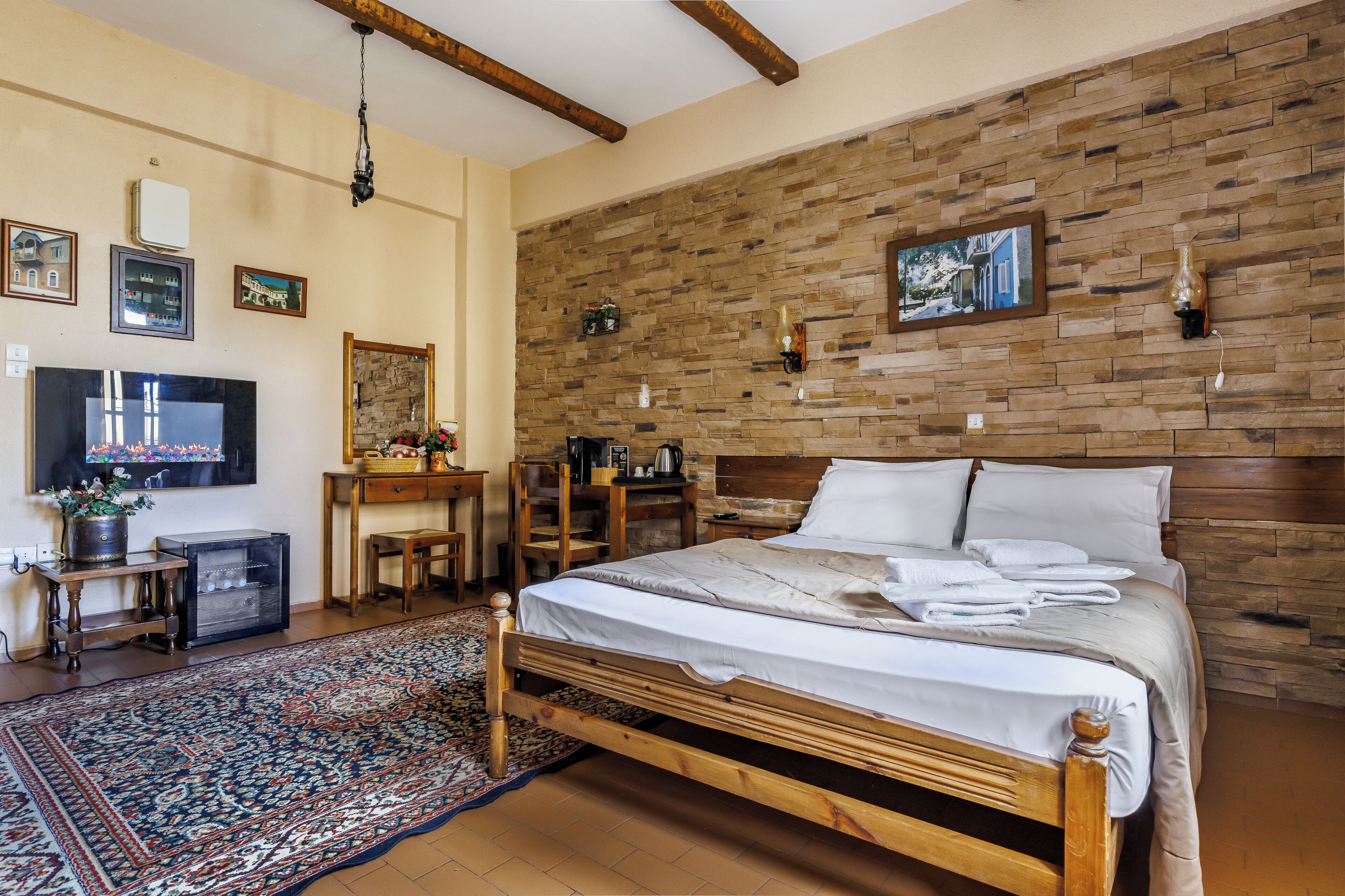 Una camera da letto con un letto di legno, una televisione, una scrivania e un muro in pietra.