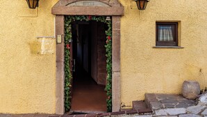A yellow building with a stone archway entrance, a small window, and a stone planter. - Rigas Hotel Arachova (Distomo-Arachova-Antikyra)