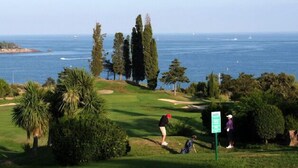 Golfkenttä, jolta avautuu näkymä merelle, ja opastekyltti, joka osoittaa parkkialueen.