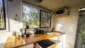 A compact kitchen with a wooden countertop, a built-in microwave, a coffee maker, and a sink.