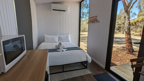 A modern bedroom with a bed, a television, and a view of the outdoors. - The Summit View by Tiny Away (Dadswells Bridge)