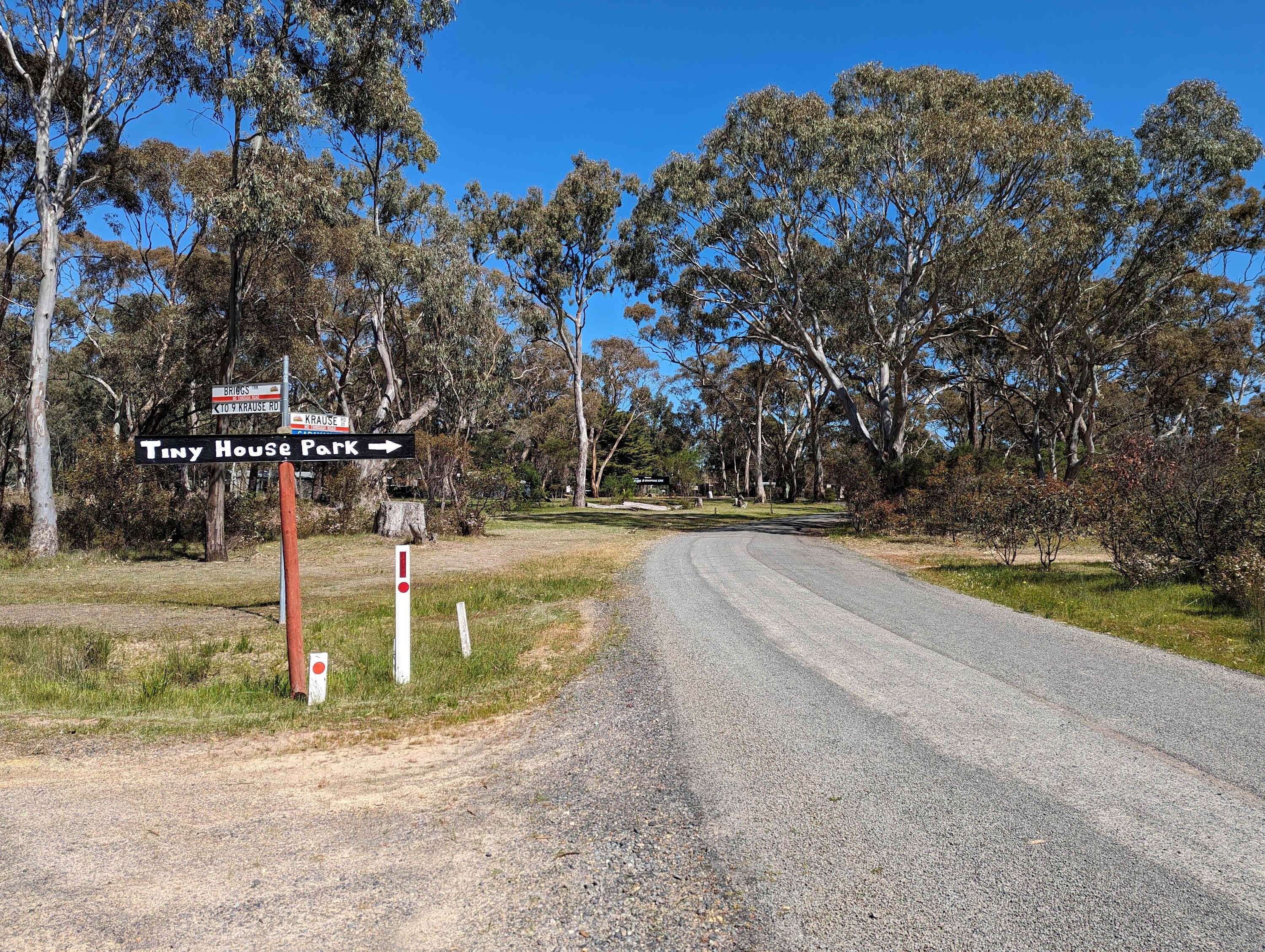 A rural road with directional signs for Tiny House Park and Krause Rd.