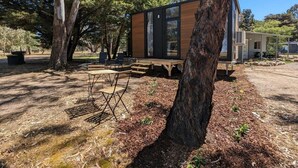 A modern house with a deck, surrounded by trees and outdoor seating. - The Summit View by Tiny Away (Dadswells Bridge)