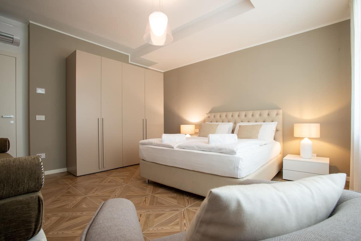 Ein modernes Schlafzimmer mit einem großen Bett, Nachttischen, einem Kleiderschrank und einer Sitzecke.