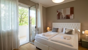 A bedroom with a large bed, a sliding glass door to a balcony, and a modern light fixture.