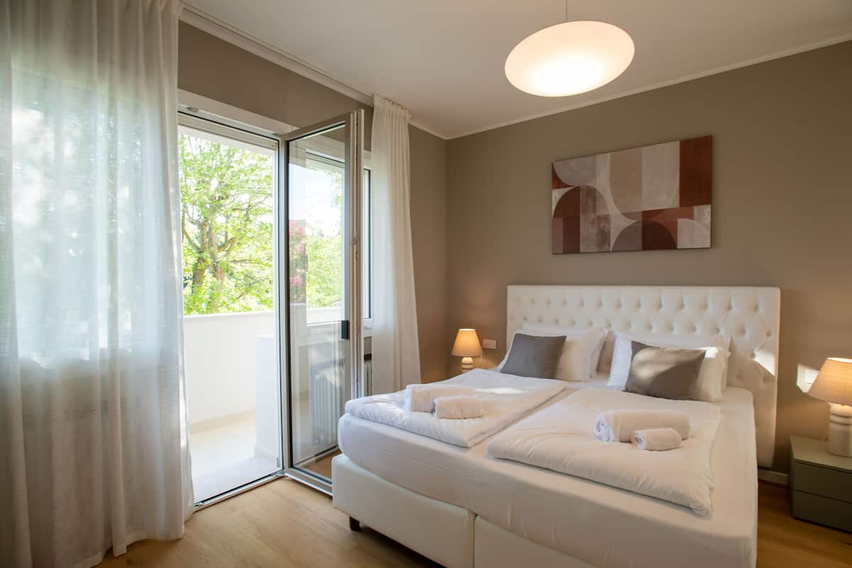 Ein Schlafzimmer mit einem großen Bett, einer Schiebetür zum Balkon und einer modernen Lampe.