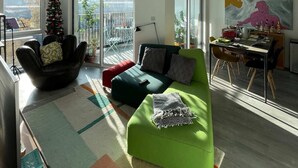 A modern living room with a green sofa, a black armchair, and a Christmas tree. - Bright 1BD Flat W/balcony - Heart of Brixton! (London)