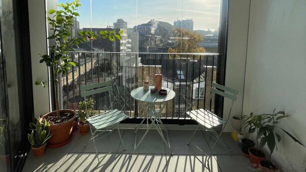 A balcony with a table and chairs, potted plants, and a view of a cityscape. - Bright 1BD Flat W/balcony - Heart of Brixton! (London)