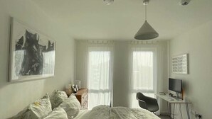 A bedroom with a bed, a desk, a chair, a computer, and a painting on the wall. - Bright 1BD Flat W/balcony - Heart of Brixton! (London)