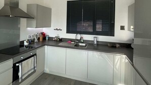 A modern kitchen with a central island, stainless steel appliances, and a window with blinds. - Bright 1BD Flat W/balcony - Heart of Brixton! (London)