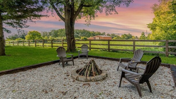 An outdoor seating area with Adirondack chairs around a fire pit, surrounded by a gravel area and a wooden fence. - Woodford Stables / Walk to Eckert's Orchard (Versailles)