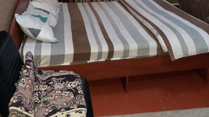 A room with a bed, a bedside table, an air conditioning unit, and curtains. - Hotel Sezim (Toktogul)