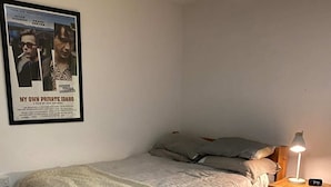 A single bed with a wooden frame, a bedside table with a lamp, and a poster on the wall. - Cosy Studio Flat - 12 Mins to British Museum! (London)