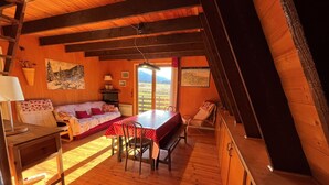 Una habitación acogedora con techo de madera, una mesa de comedor, un sofá y una cama.