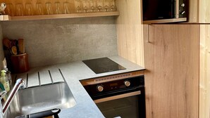 Una cocina compacta con microondas integrado, estufa y pileta.