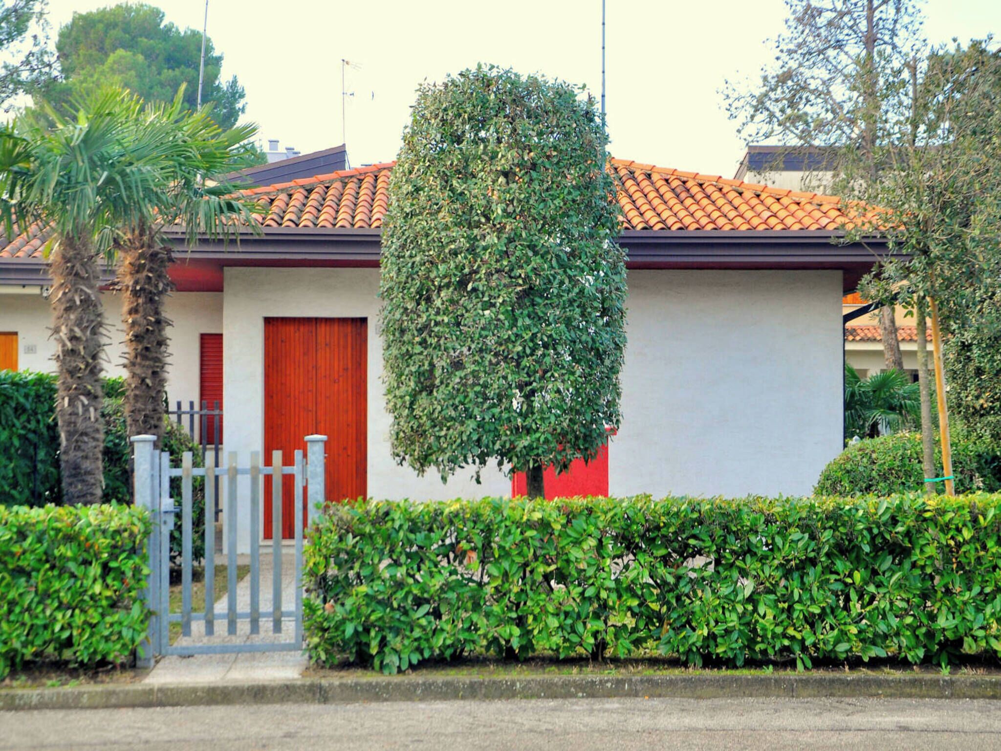 A residential building with a red door, a small garden, and a metal gate.