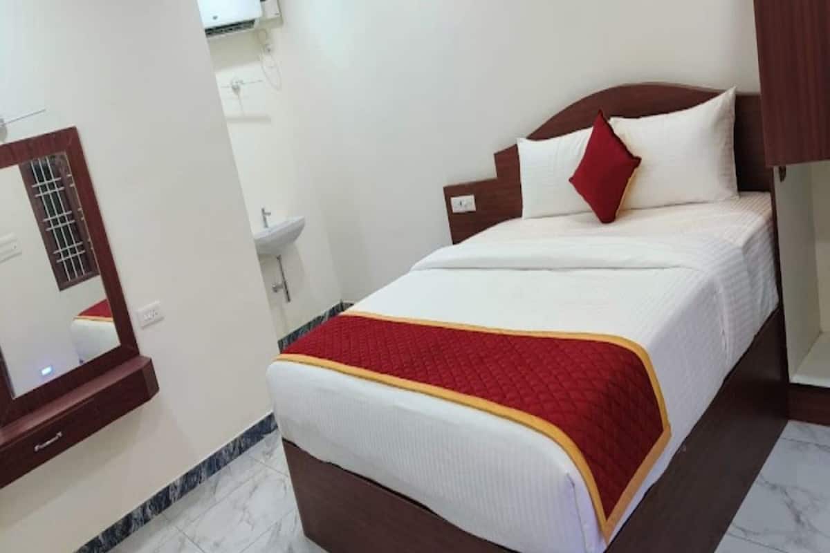Habitación de hotel con cama, espejo, lavamanos y equipo de aire acondicionado.