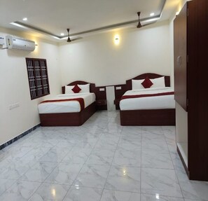 A hotel room with two beds, a wardrobe, a ceiling fan, and an air conditioning unit.
