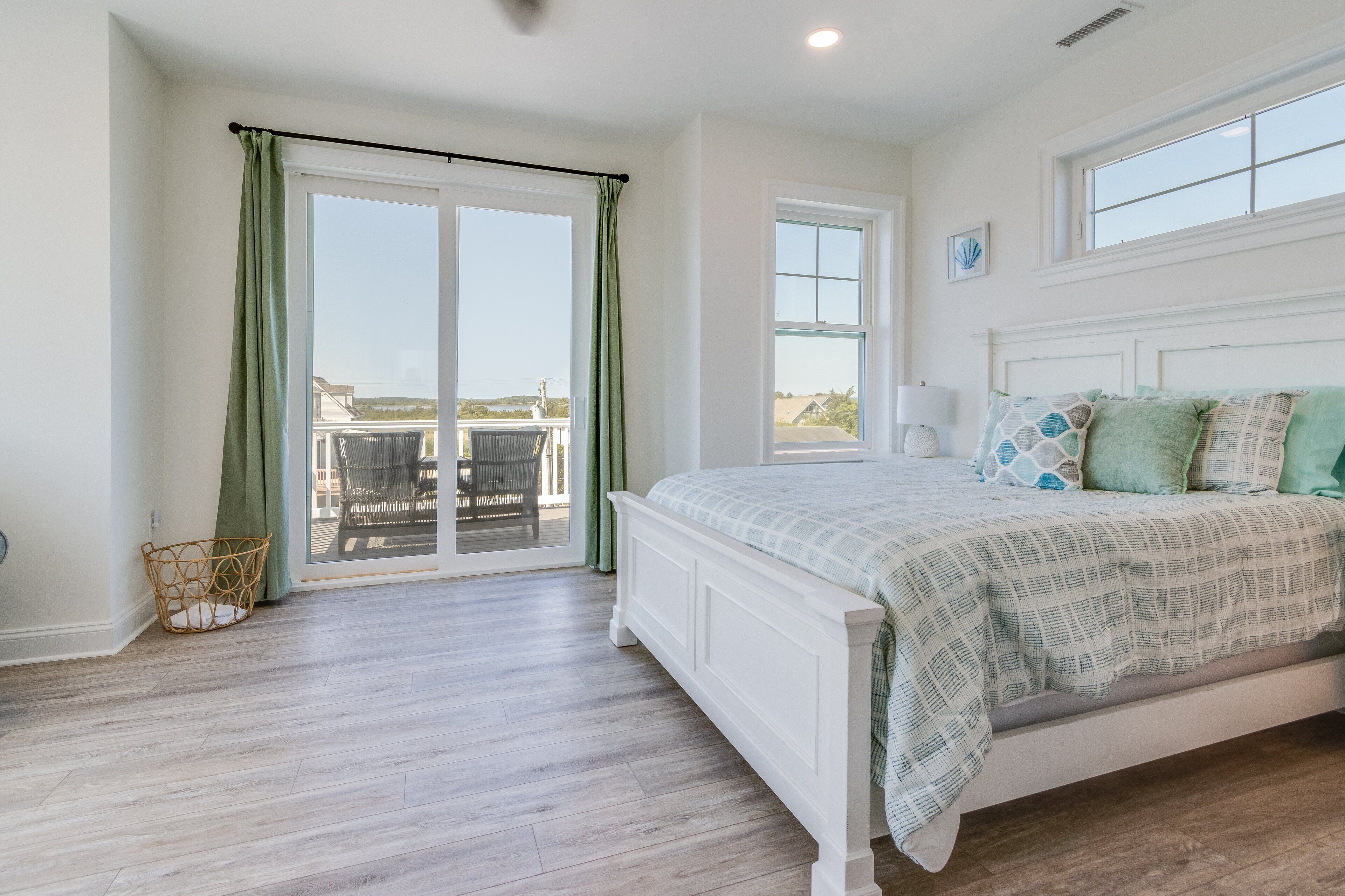 A bedroom with a large bed, a sliding glass door to a balcony, and a view of the outside.