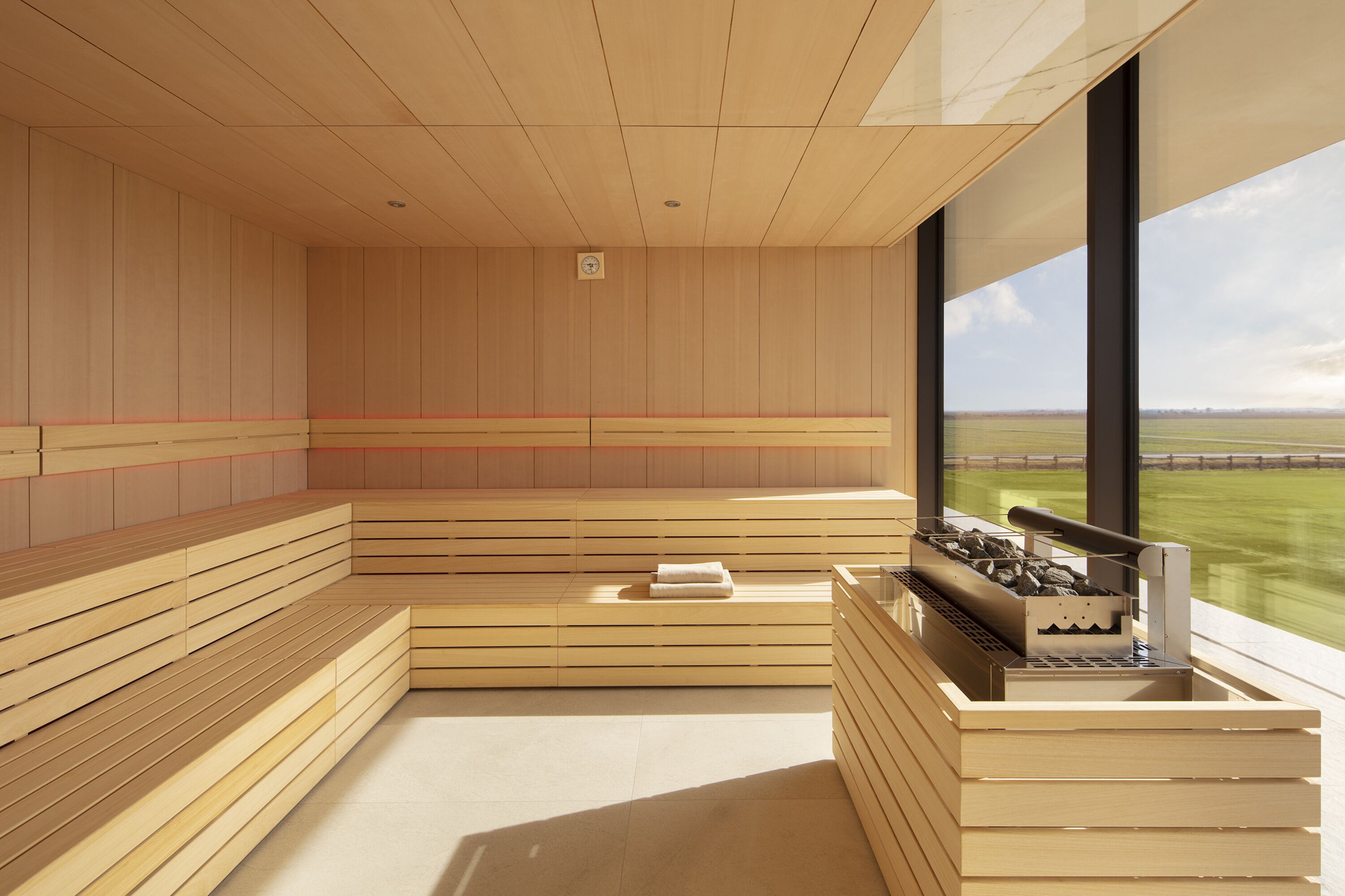 Una sauna con bancos de madera y una mesa para sauna, ventanas amplias y vistas al exterior.