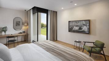 A modern hotel room with a large bed, a desk, a chair, and a view of the outdoors.