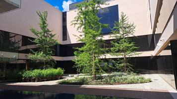 A modern building with a reflective pool, surrounded by greenery and trees.