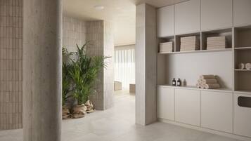 A modern bathroom with a tiled floor, a large potted plant, and neatly arranged towels and toiletries on shelves.