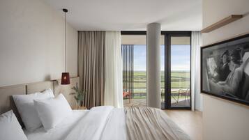 Ein modernes Hotelzimmer mit einem großen Bett, Blick auf die Landschaft und einem gerahmten Bild an der Wand.