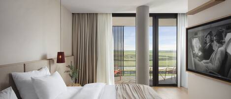 Una habitación de hotel moderna con una cama grande, vistas al campo y un cuadro en la pared.
